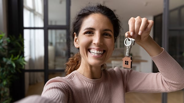 A woman holding a key with a house keychain.