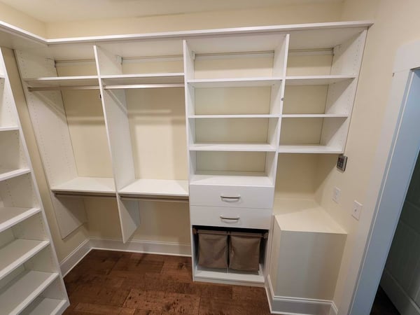 Walk-in closet with shelves, hanging rods, and hampers.