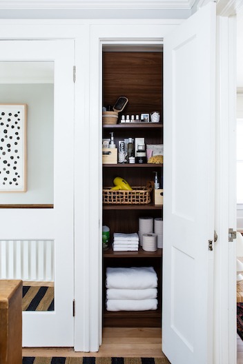 Reach-in, linen closet storage against sloped ceilings with dark wood.
