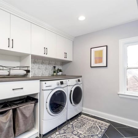 Historic home laundry room renovation with white cabinetry and decorative backsplash
