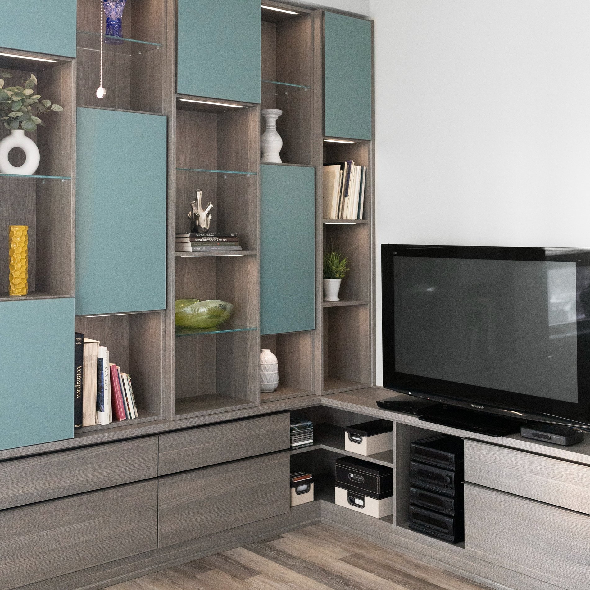 Transitional media design with open cubbies, blue glass doors, and lower drawers.