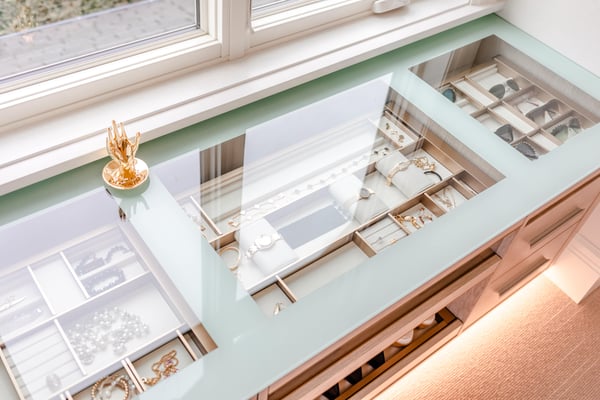 View of cabinet glass top displaying jewelry trays in the top drawer