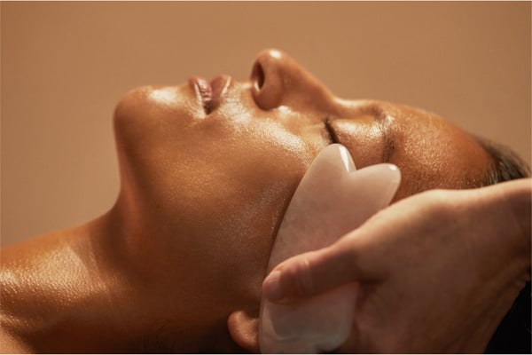 Woman getting a gua sha, sculpting facial.