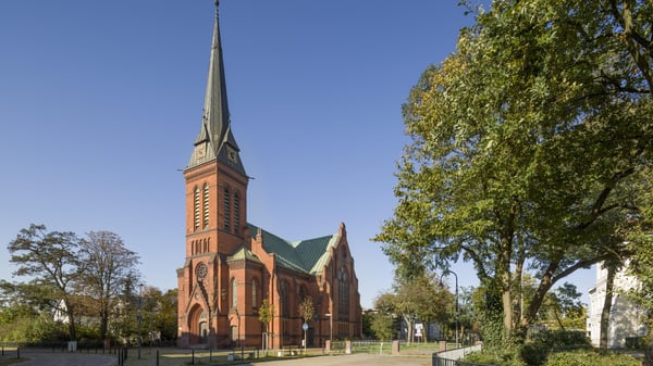 Kirchengebäude an einer Straße mit Bäumen.