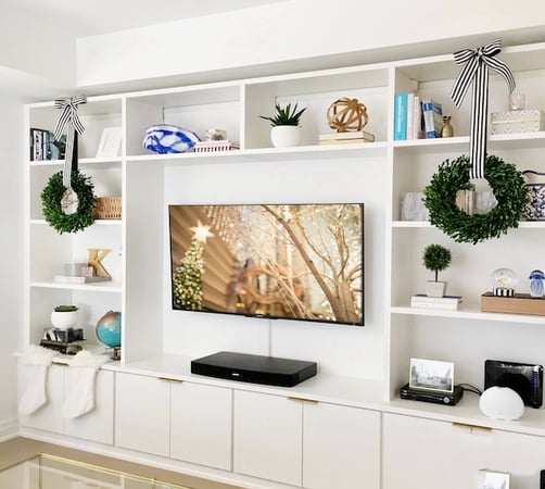 Custom white Entertainment center with a TV, has drawers, doors, and shelves
