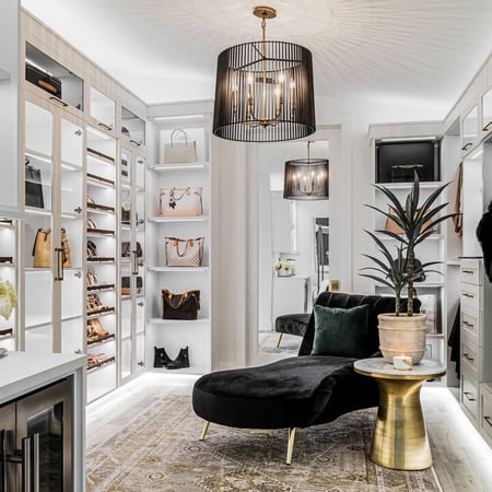 Custom luxury walk in closet in clean white finish with open shelving, led lighting and cabinets by California Closets