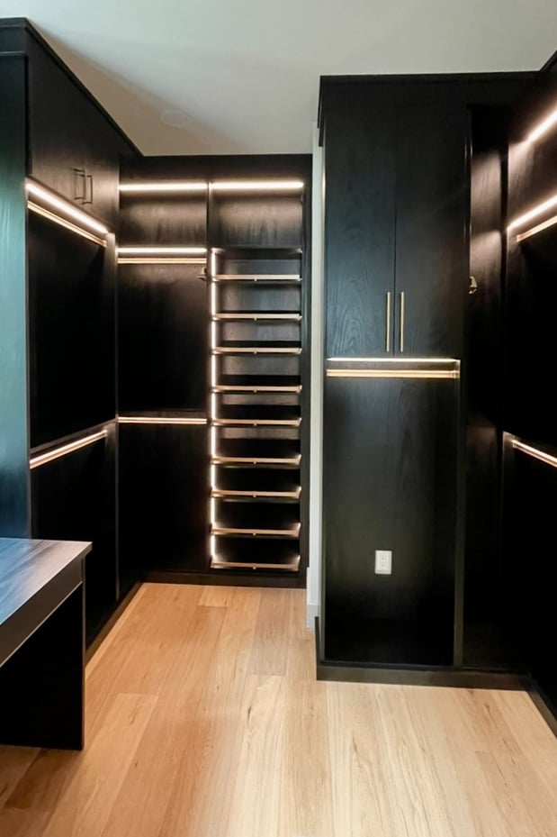 Walk-in closet in Shadow Black finish featuring an Everstyle vanity drawer, Pub House knurled handles in satin brass, and integrated lighting for a sleek, modern, and organized space.
