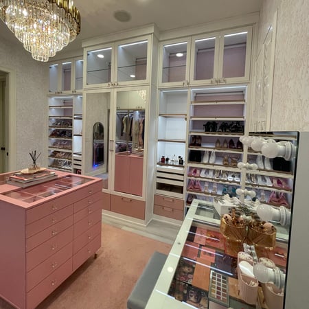 A Barbie-inspired closet in washed white with petal pink accents and elegant gold hardware.