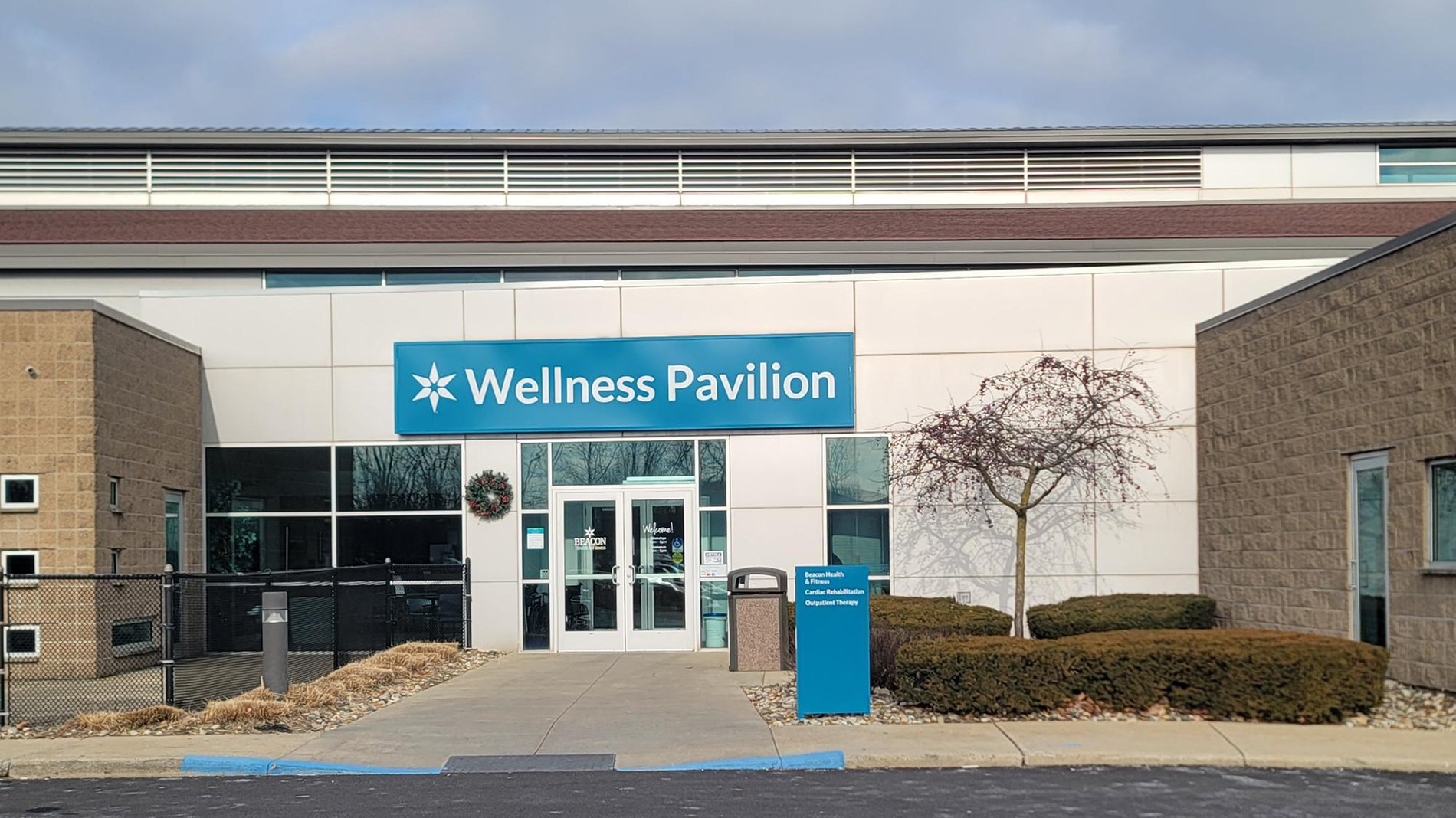 A large white building with a teal sign that reads, "Wellness Pavilion"