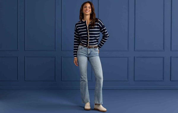 Woman is wearing a cardigan and blue jeans.