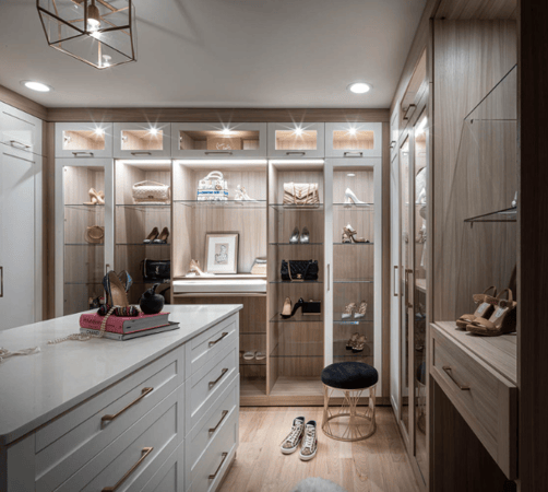 Img 6 California Closets Westchester County New York Two Toned White and Beige Large Walk-in Luxury Closet with Glass Shelving, Glass Doors, Lighting, and a Custom Center Island with Custom Jewelry Drawers