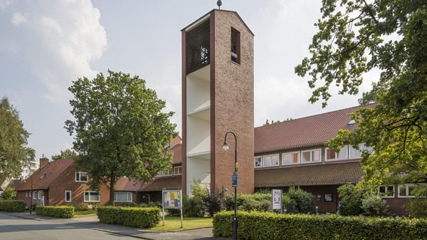 Ein Kirchengebäude mit einem modernen Glockenturm aus Backstein.