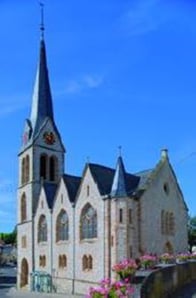 Außenansicht der Kirche vor blauem Himmel. Der Kirchturm ragt besonders heraus.