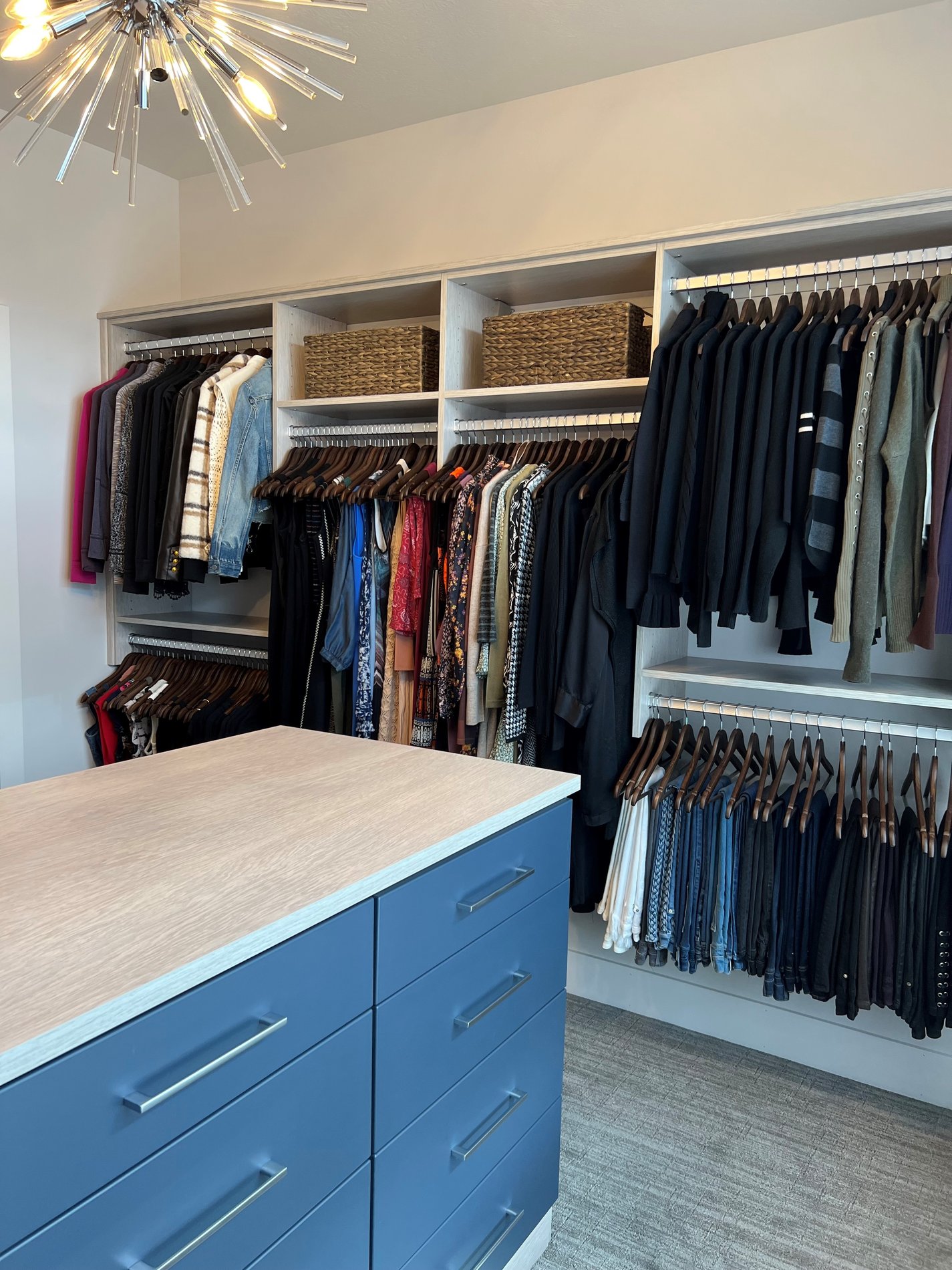 Custom walk in closet with an abundance of hanging space, a center island, and drawers located in Cleveland Ohio.