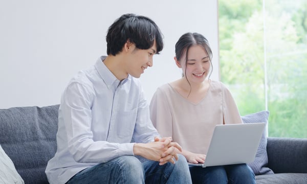 ソファでPCを眺めるカップル