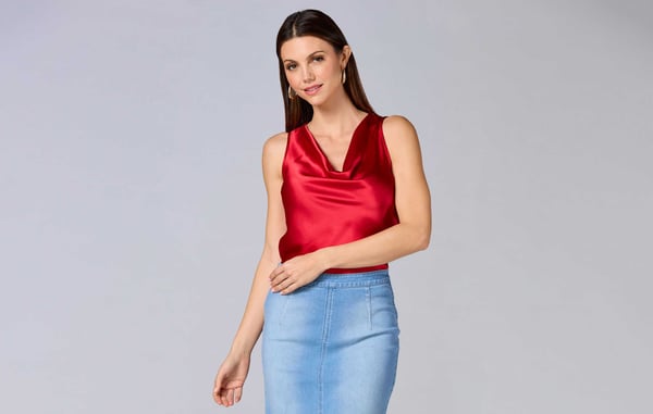 Woman is wearing a red sleeveless blouse and a denim skirt.
