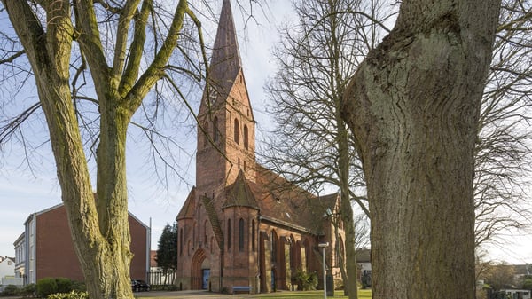 Das Kirchengebäude umrahmt von Bäumen.