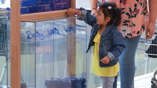 Child putting a blue token in a community grant box