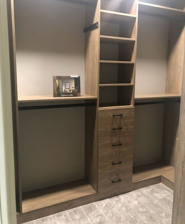 Brown walk-in closet with drawers, shelving, and hanging space.