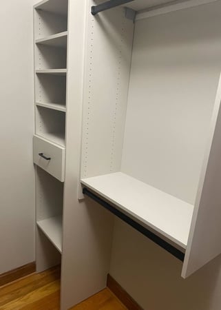 A white walk-in closet featuring hanging dividers and shelving.