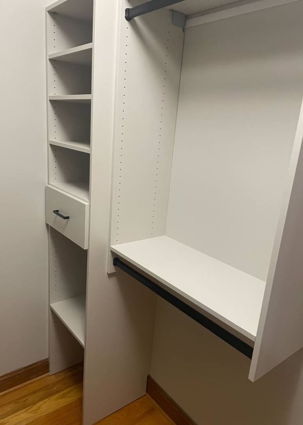 A white walk-in closet featuring hanging dividers and shelving.