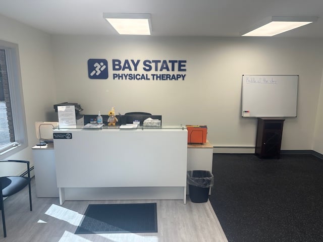 RI-WestWarwick-BSPT front desk and waiting room area Bay State PT logo on wall above desk.