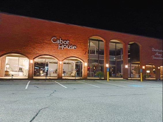 Storefront of the Burlington location of Cabot House Furniture at night.