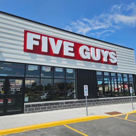 Exterior photograph of the Five Guys restaurant at 595 Taunton Road East in Oshawa, Ontario, Canada.