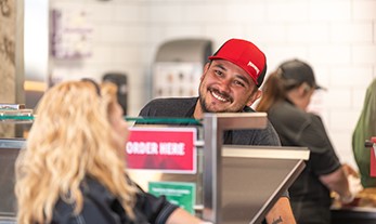 A person in a red hat smiling at a customer
