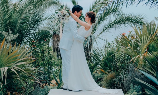 南国の植物の前でポーズをとる新郎新婦