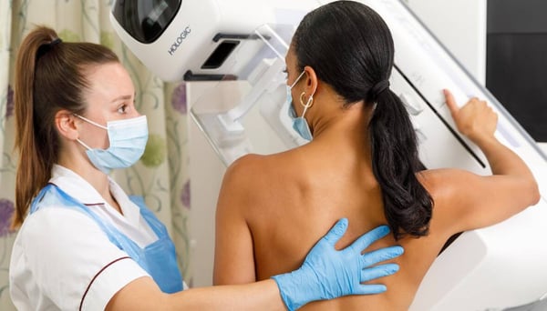 Radiologist supporting patient having a mammogram