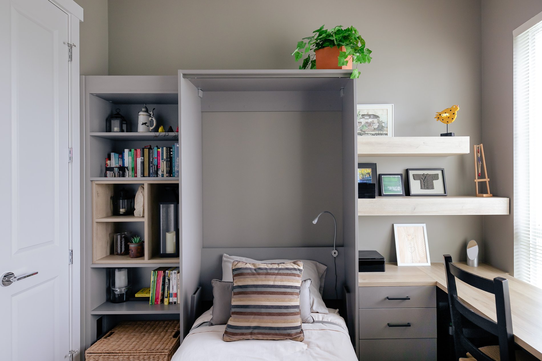 An open wall bed with a built in desk on one side and shelving on the other side