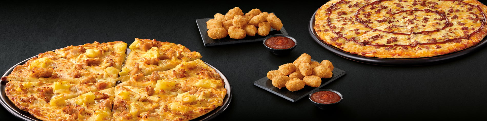 Image of the On The Double® Feast pizza deal from Debonairs Pizza Mandalay: 2 Real Deal pizzas and 2 15 Chicken Shots with dipping sauces against a black background.