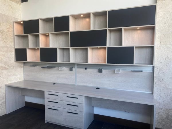 Custom built desk for two side by side with cabinets and cubbies above