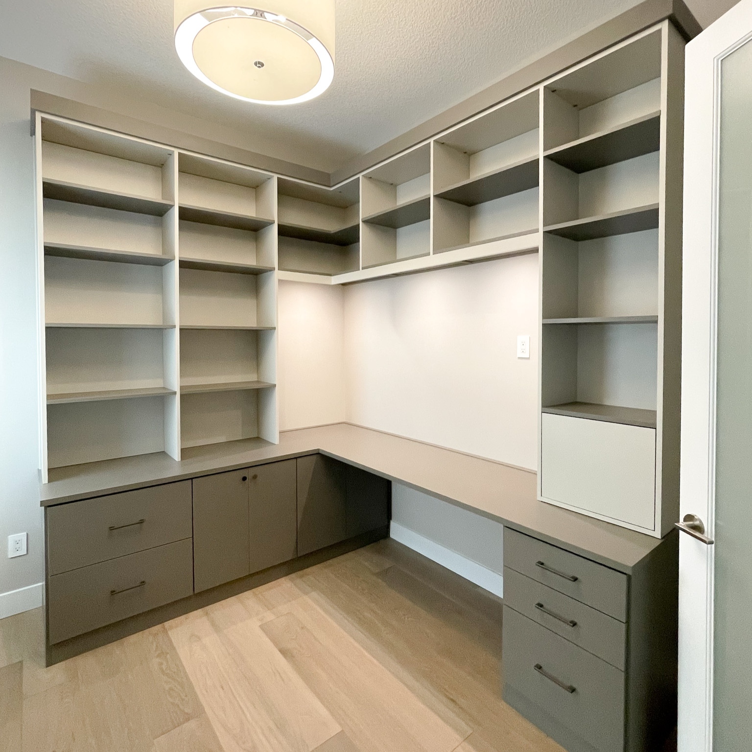 Home office with floor to ceiling storage, open shelving, and drawers.