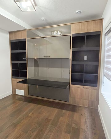 Modern wall bed with a high gloss finish, contrasting dark shelving, and a desk and shelf on front.