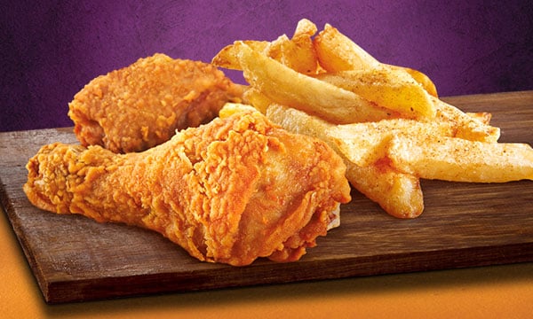 Fried chicken and a portion of hand-cut chips on a wooden board.
