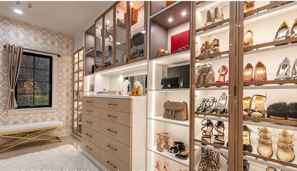 luxe walk in closet with lighting and glass doors, accenting shoes and hand bags