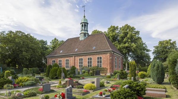 Kirchengebäude aus Backstein umgeben von einem Friedhof.
