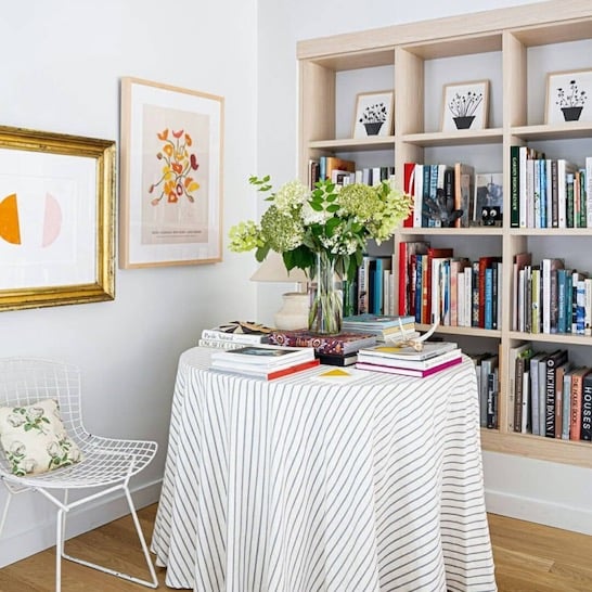 Reading area with built-in library shelving, vase with flowers and neutral decor.