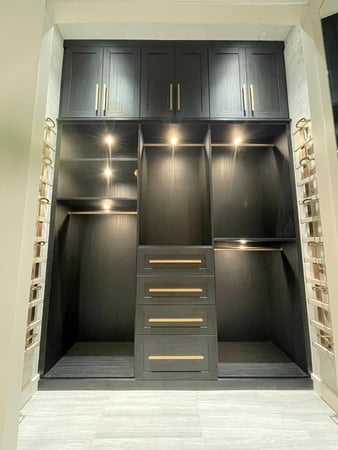 Dark toned closet with shelving, lighting and a accessory tray on both sides
