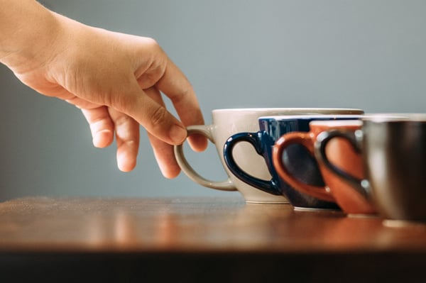 Man reaches for coffee, a trigger for tinnitus in some.