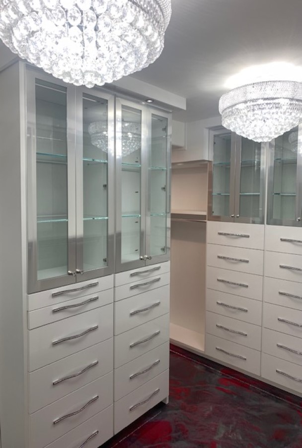 White walk-in closet master closet with aluminum framed glass doors and custom handles on multiple banks of drawers