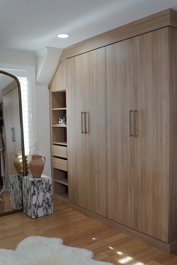 Light wood tone built-in wardrobe under a slanted ceiling.