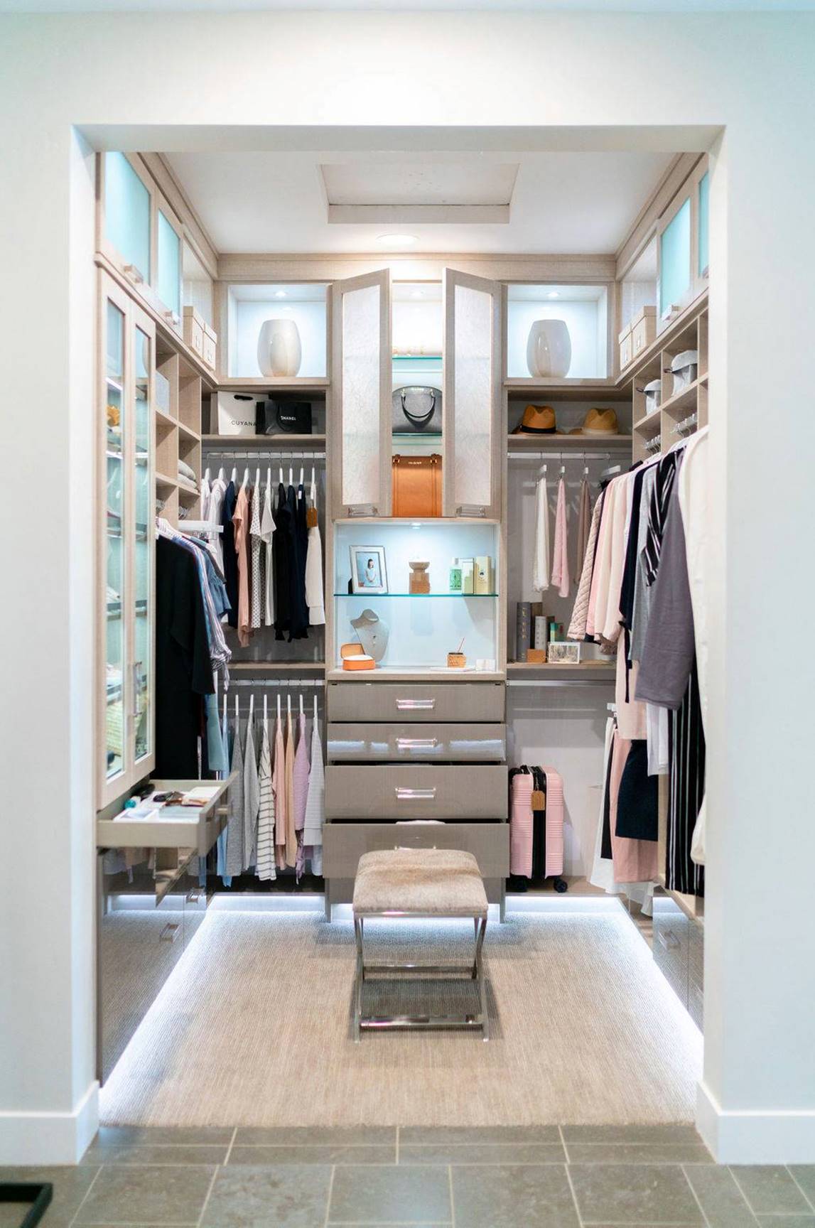 Luxe white walk-in closet with lighting and glass doors
