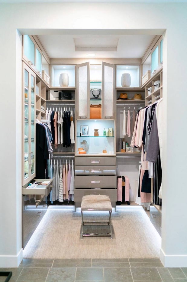 Luxe white walk-in closet with lighting and glass doors