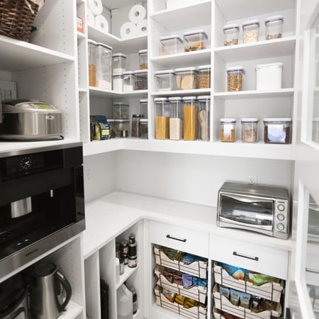California Closets pantry designed in a white finish with a countertop, open shelves, baskets with liners, vertical shelving for cookie sheets.