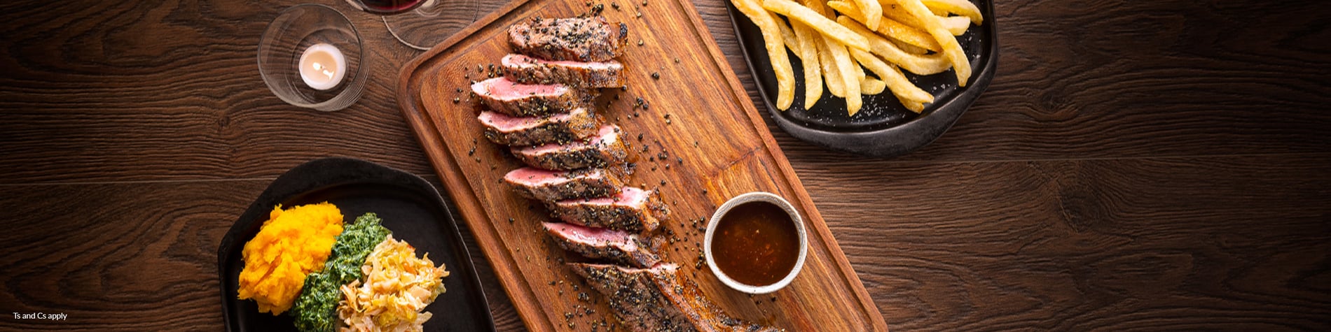 Sirloin Steak on a board, surrounded by sides and sauces.