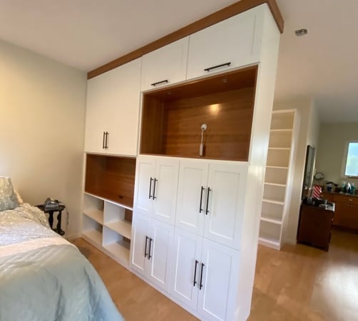 White storage cabinet and media center with brown accents and crown molding.