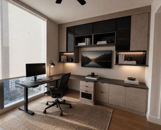 Modern custom home office with wood cabinetry, glass cabinets, built-in desk, shelving, and lighting.